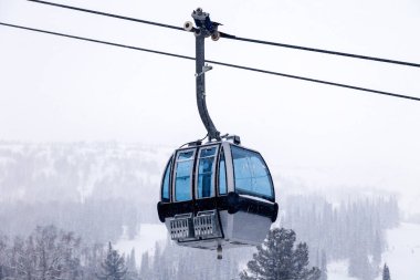Ski lift arka plan mavi yansıtılmış camına karla kaplı dağlar, kar fırtınaları, yaprak dökmeyen ağaçları ile teleferik ile kapalı bir kabin üzerinde. Yazıt, kopya alanı kavramı yer