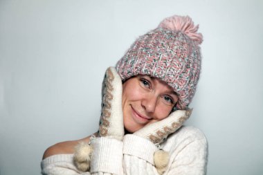 İzole portre güzel genç Kızıl saçlı kız yeşil gözleri tek omuzlu, süveter desen mittens kürk ponpon, pembe örgü şapka Studio beyaz arka plan üzerinde yana giyinmiş ile beyaz