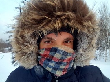Portre portre genç esmer adam frost ile kaşları rakun kürk başlık ve kareli atkı yüz kapsayan ile sıcak ceketli kapalı. Sert hava koşulları Kanada, Kuzey Kutbu'nda kavramı