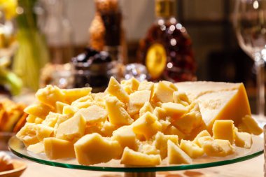 Plaka closeup adet çeşitli yemekler arasında masadaki şölende İtalyan parmesan ile. Kavram Doğum günü, büfe, konyak ya da viski sunum, peynir tatma