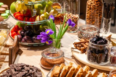 Closeup snacks, fresh and dried fruits, pieces parmesan cheese, honeycombs, dark chocolate, cinnamon sticks, nuts, biscotti. Concept degustation premium alcohol at opening of the clothes store