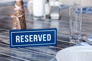 Closeup ahşap mavi beyaz dikdörtgen plaka restoran ayarı, peçete, tuz karabiber, vazo çiçekler, Gözlük, beyaz seramik kaplamalar uzaklığı gri vintage tablo üzerinde kelime ayrılmış duran ile