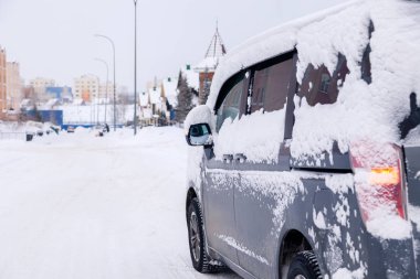 Kapalı gri minibüs. Kirli araba, şehir merkezine karla kaplanmış.