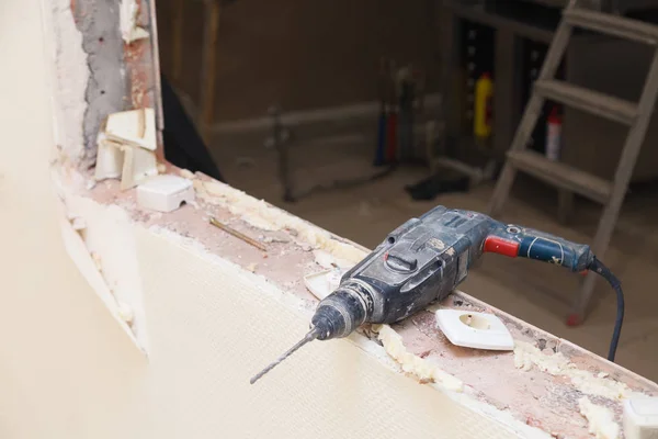 Portre profesyonel inşaat tozlu matkap, onarım, inşaat, yeniden yapılanma, tuğla, merdiven arka plan üzerinde zımba. Kavram yükleme ve ofis binası kapı ve pencerelerin sökülmesi