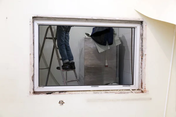 Trabajador en uniforme se para en escalera en la abertura de la ventana. Concep —  Fotos de Stock