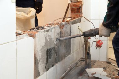 Tozlu üniformalı adam profesyonel çalışan tuğla, beton duvarlar ve kiremit perforator ile tatili. Kavramı revizyon, yenileme, ofis, Restoran mutfağında duvarlarının yeniden geliştirilmesi