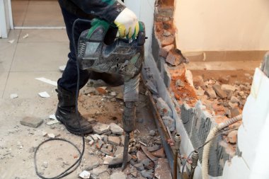 Tozlu üniformalı adam profesyonel çalışan tuğla, beton duvarlar ve kiremit perforator ile tatili. Kavramı revizyon, yenileme, ofis, Restoran mutfağında duvarlarının yeniden geliştirilmesi
