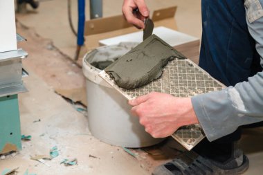 Closeup builder'ın el mala banyoda tutkal ile seramik karo çimento tutkal smear. Kavram tadilat onarım, bakım, sözleşme kiremitçi, inşaat tamirci takım