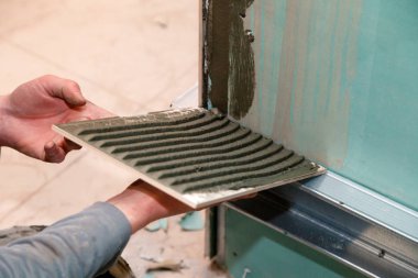 Portre profesyonel Oluşturucusu adamın el tutkallar seramik yapıştırıcı banyo ile. Kavram tadilat onarım, bakım, sözleşme kiremitçi, inşaat tamirci takım