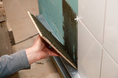 Portre profesyonel Oluşturucusu adamın el tutkallar seramik yapıştırıcı banyo ile. Kavram tadilat onarım, bakım, sözleşme kiremitçi, inşaat tamirci takım