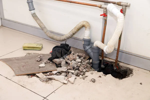 Tuğla yerde kırık taşlarla delik plastik Polipropilen gri kanalizasyon boruları tamir. Boru yerine, su kaçağı, su temini, transferini kavramı lavabolar