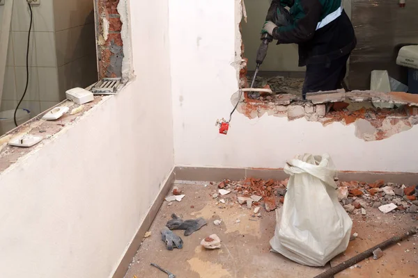 Tozlu üniformalı adam profesyonel çalışan tuğla, beton duvarlar ve kiremit perforator ile tatili. Kavramı revizyon, yenileme, ofis, Restoran mutfağında duvarlarının yeniden geliştirilmesi