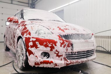 Rusya Kemerovo 2019-01-05 Suzuki Swift parlak kırmızı küçük araba beyaz köpüklü oto yıkama, oto temizlik için profesyonel kimyasal deterjan. Dış ve iç için kapsamlı bakım kavramı