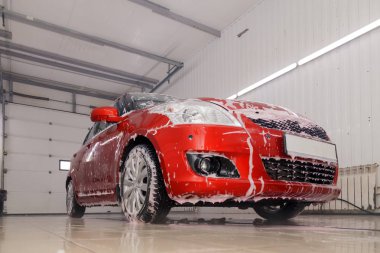 Rusya Kemerovo 2019-01-05 Suzuki Swift parlak kırmızı küçük araba beyaz köpüklü oto yıkama, oto temizlik için profesyonel kimya. Dış ve iç bir araba için kapsamlı bakım kavramı