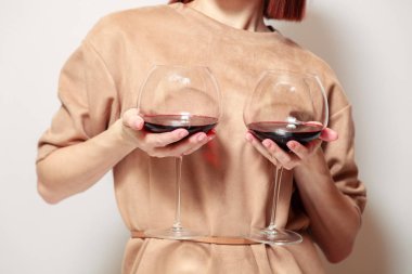 Genç, kızıl saçlı, beyaz arka plandaki şarap garsonu. Gülümse, iki kadeh kırmızı şarap tut, meme gibi. Konsept alkolizm, alkol bağımlılığı, kötü alışkanlık, harika nadir şaraplar, şarap koleksiyonu