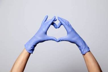 Lateks lastik eldivenli bir elin yakın çekimi. Mor eldivenler katlanmış.