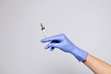 Kapalı kapaklı şeffaf şırınga tutan kauçuk mor eldivenli doktor eli. Beyaz arka planda izole edilmiş. Aşıların, aşıların, kuduz aşısının reddedilmesi.