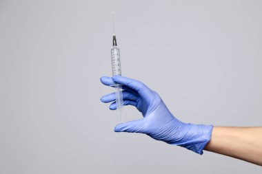 Plastik lateks mor eldivenli yakın çekim doktoru elinde şeffaf şırınga tutuyor. Beyaz arka planda izole edilmiş. Aşıların reddedilmesi, HIV enjekte edilmesi, AIDS salgını, hepatit önleme