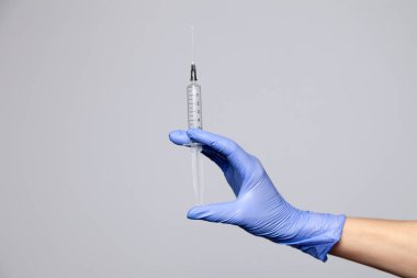Plastik lateks mor eldivenli yakın çekim doktoru elinde şeffaf şırınga tutuyor. Beyaz arka planda izole edilmiş. Aşıların reddedilmesi, HIV enjekte edilmesi, AIDS salgını, hepatit önleme