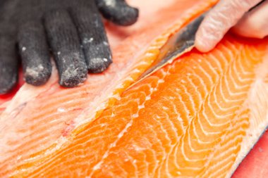 Yakın plan taze somon balığı kırmızı kesikli bıçaklı fileto hazırlıyor.