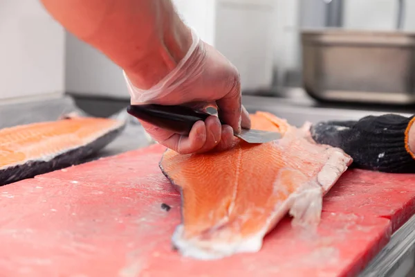 Closeup whole fresh salmon fish preparing fillet with knife on r