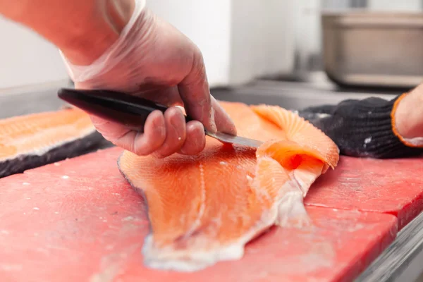 Closeup whole fresh salmon fish preparing fillet with knife on r