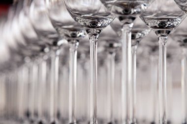 Birçok şeffaf kristal şarap kadehleri kahverengi satırda duruyor 