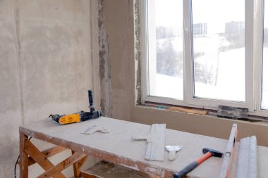 Büyük bir boş odada pencerede ahşap iskele standı, yeniden