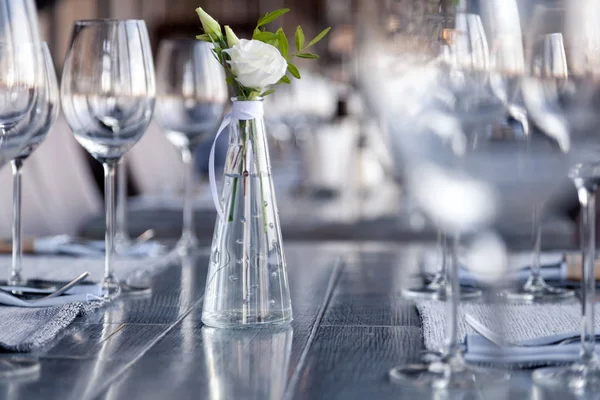 Modern restaurant setting, glass vase with bouquet flowers on ta