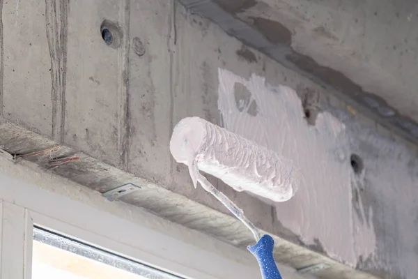 Paint roller and primer on the wall above the window. Concept of — Stock Photo, Image