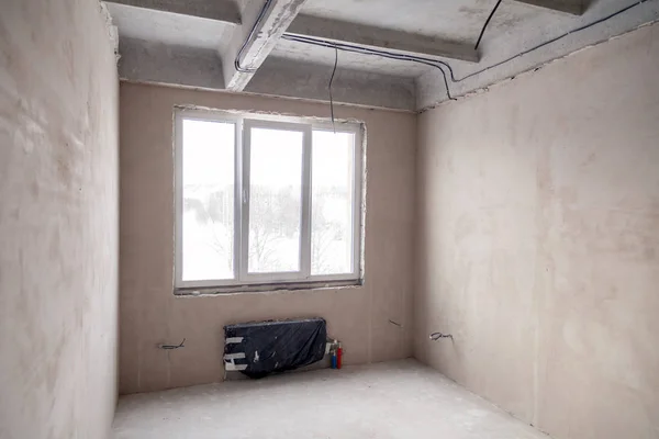 Empty room with a window and a battery in a house under construc