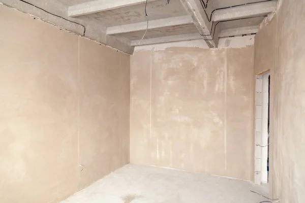 Empty room in a house under construction, plastered walls, scree