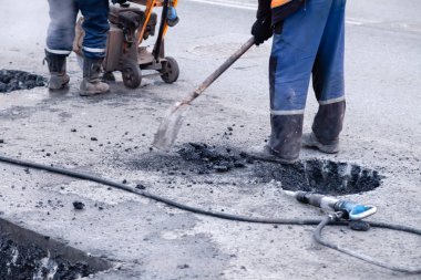 Üniformalı profesyonel işçiler yolu onarıyor, önlerini kesiyor.