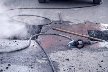 Yakından çekiç, profesyonel aletler, asfalt dilimleri ve kırıntılar.
