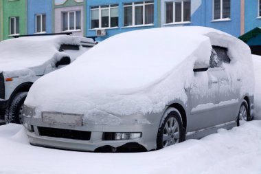 Kar larla kaplı araba kışın konut binasının otoparkında duruyor. kötü hava, kar yağışı, sert hava koşulları, don, kar fırtınası, araba motoru bir kez başlamadı