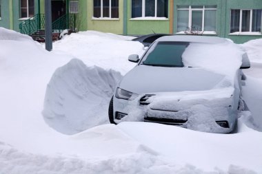 Kar larla kaplı araba kışın konut binasının otoparkında duruyor. kötü hava, kar yağışı, sert hava koşulları, don, kar fırtınası, araba motoru bir kez başlamadı