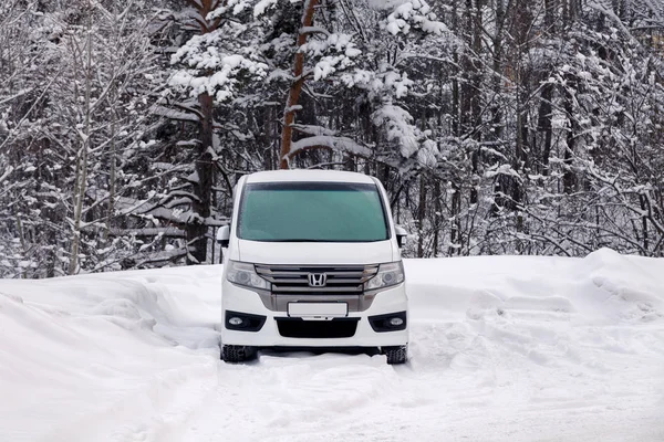 Rusia Kemerovo 2019-01-07 blanco limpio Japón minibús coche Honda Stepwgn spada cubierto de nieve. Vista frontal en bosque de invierno. Concepto nevada, malas condiciones climáticas del norte, viajar en familia grande — Foto de Stock