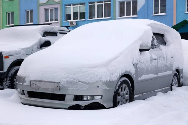 Samochód pokryty śniegiem stoi na parkingu budynku mieszkalnego w zimie. Oncept złej pogody, opady śniegu, trudnych warunkach pogodowych, mróz, Zamieć, silnik samochodowy nie uruchomić — Zdjęcie stockowe