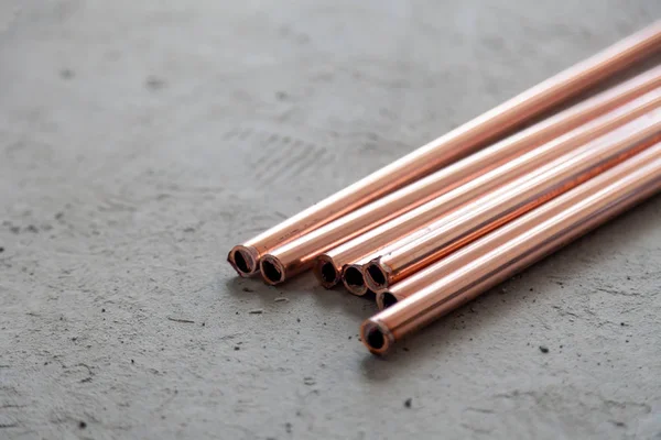 Close-up many new copper dyne pipes on the concrete floor. Conce — Stock Photo, Image