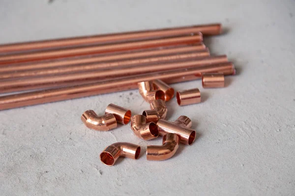 Many new copper pipes fittings on the concrete floor. Concept installation, replacement of plumbing, repair of the pipeline, professional master plumber, leakage pipe — Stock Photo, Image