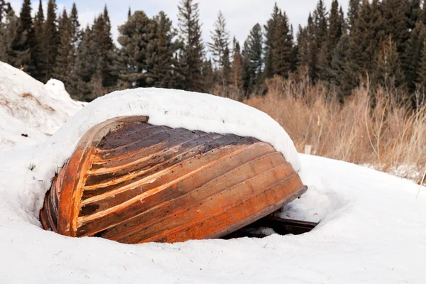 Oude houten vernietigd overstroomde vissersboot liggen in de sneeuw aan wal — Stockfoto
