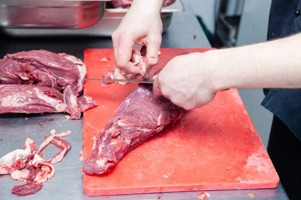 Closeup hands of man butcher chef cook cuts pork and beef meat