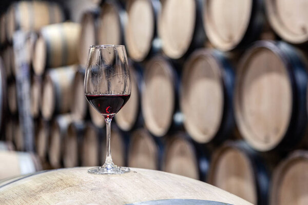 Closeup glass with red wine on background wooden wine oak barrel