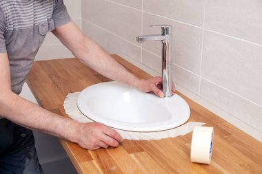 Closeup hands of a professional plumber worker installs a white  clipart