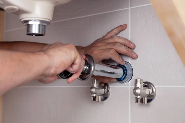 Fregadero de fijación de mano de fontanero masculino de primer plano en baño con azulejo wa —  Fotos de Stock