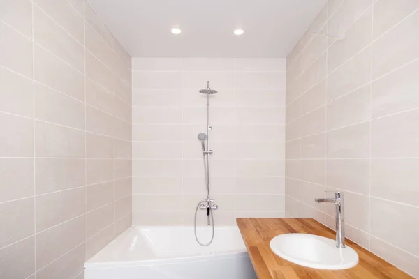 Empty new bathroom with beige ceramic rectangular tiles, large b