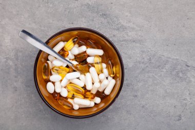 Tabletler, haplar, kapsüller, gri arka planda kahverengi kasedeki uyuşturucular.