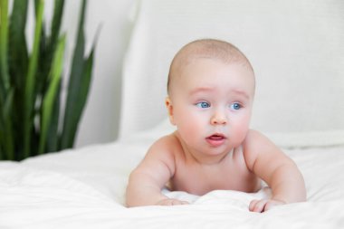 Beautiful baby playing with legs in white bedroom on white background