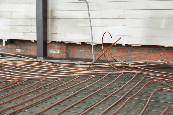 Doblado nuevas tuberías de cobre por el suelo de hormigón — Foto de Stock