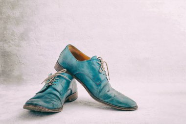 Bir çift eski deri mavi bağcıklı atılmış bot.